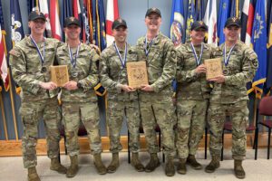 cadets on combat shooting team dressed in fatigues, holding plaques and smiling