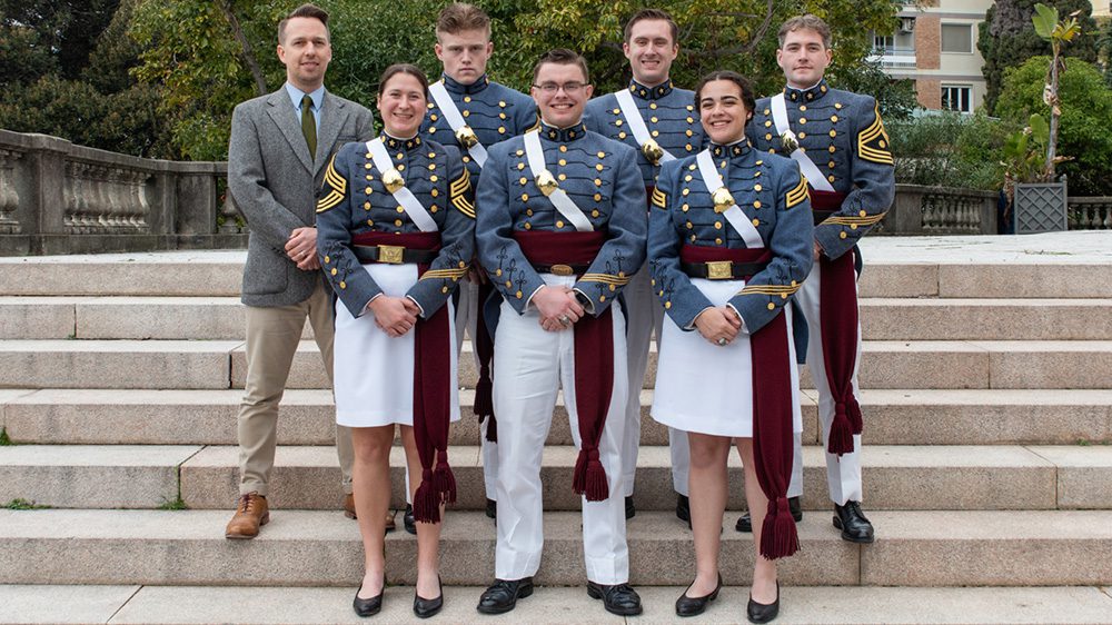 cadets in dress dyke and their instructor posing on concrete steps