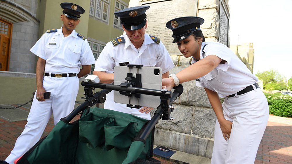 three cadets look at and point to screen on tablet