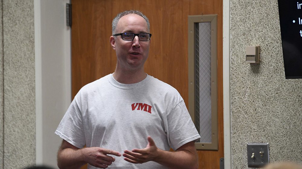 man in white VMI t-shirt talking