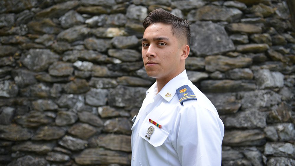 cadet in class dyke standing in front of stone wall