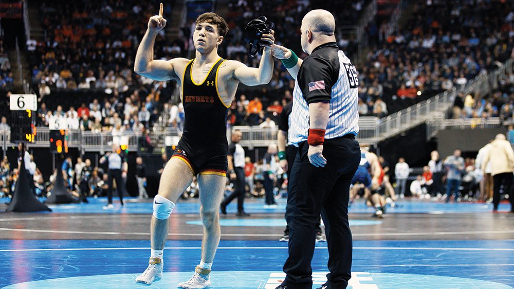 wrestler and referee standing on wrestling mat