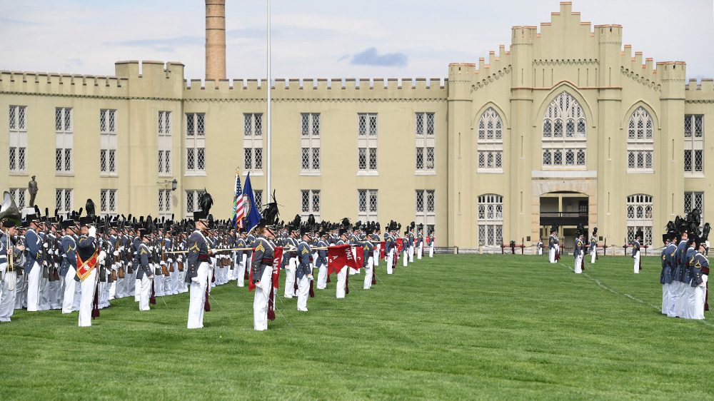 cadets in parade formation with old barracks in the background