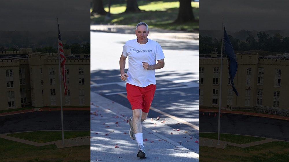 man in white shirt and red running shorts running on sidewalk